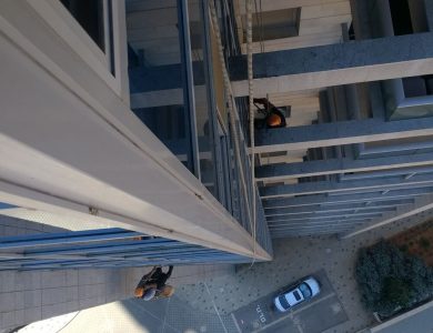עובדי ניקוי בגובה מנקים חלונות באמצעות סנפלינג על מבנה מודרני - פיגומים וחבלים